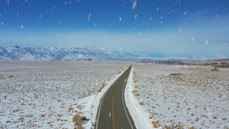 Winding-endless-American-rural-road-during-heavy-snowfall,-aerial-view