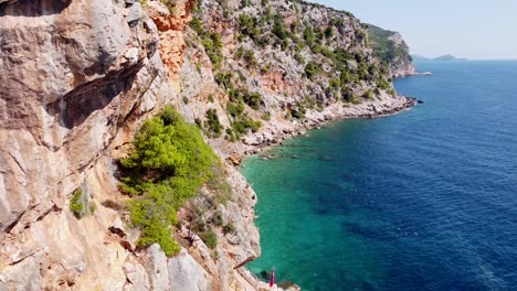 Tourists-Walking-to-Hidden-Pasjaca-Beach-in-Dalmatia,-Croatia---Aerial-Circling-Reveal