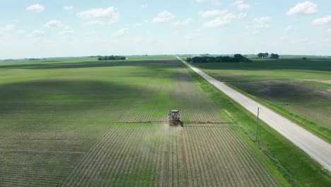 Aerial,-tractor-spraying-pesticide-on-crops-in-rural-agricultural-farm-field