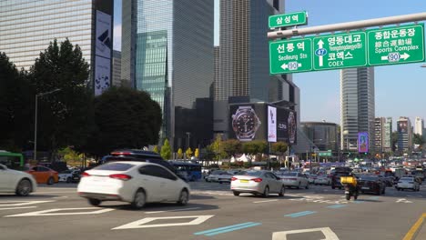 Busy-car-Traffic-at-Samseong-Station-of-Seoul---Cars-driving-on-Yeongdong-road-passing-by-Coex,-Grand-Intercontinental-Hotel,-Parnas-and-Trade-Tower,-STtown-Artium-buildings-on-a-sunny-day