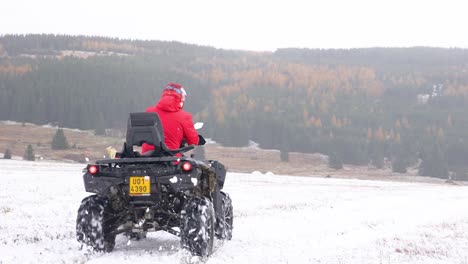 The-person-driving-an-ATV-fast-on-a-snowy-field
