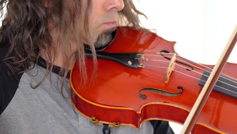 Close-up-of-ethnic-musician-in-grey-shirt-with-long-hair-and-goatee-playing-music-on-red-viola