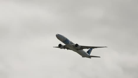 Commercial-Airplane-In-Flight-Climbing-Through-Grey-Cloudy-Sky-During-Daytime