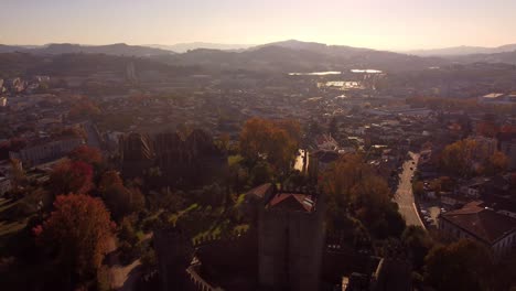 Medieval-castle-building-and-cityscape-of-Guimaraes-city-in-Portugal,-aerial-drone-shot-during-sunset
