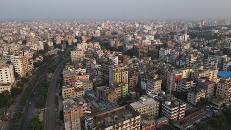 Aerial-View-Over-Dense-Metropolitan-Cityscape-Condominiums-With-Highway-Running-Past