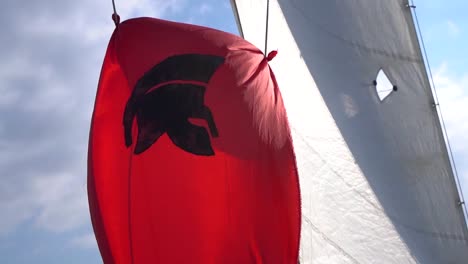 Rote-Spartanische-Flagge,-Die-An-Einem-Sonnigen-Tag-Auf-Einem-Segelboot-Im-Wind-Flattert