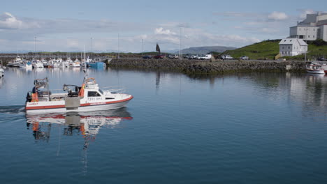 Small-white-boat-sailing-into-the-sea-from-Stykkisholmur-marina,-Iceland