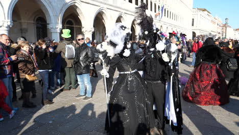 Couple-wearing-black---white-dresses-and-masks,-pose-in-St-Mark’s-square