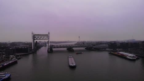 Aerial-View-Of-Raised-Spoorbrug-Railway-Bridge-Over-Oude-Maas-On-Cloudy-Day-With-Boats-Moving-Past