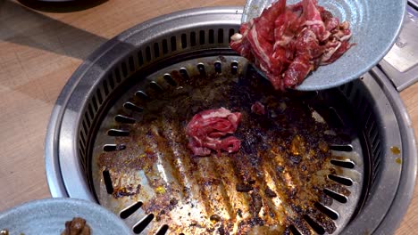 Chef-using-chopsticks-to-put-raw-beef-into-hot-pan,-close-up-view