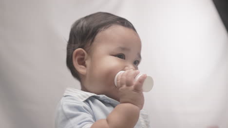 Süßer-Kleiner-Junge-Nagt-An-Plastikflasche-Mit-Weißem-Hintergrund