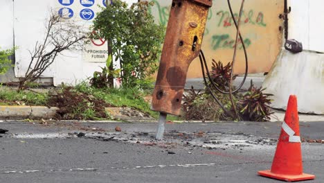 Hydraulic-breaker-bulldozer-breaks-asphalt-in-Panama-City,-Panama,-close-up,-Road-digging-to-repair-or-replace-water-pipes