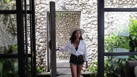 Joven-Modelo-Asiática-Entrando-A-Una-Gran-Sala-De-Estar-En-Una-Villa-Tropical-De-Lujo-En-Bali,-Indonesia,-En-Un-Día-Soleado