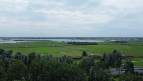 Aerial-reveal-shot-of-traffic,-fields-and-Kagerplassen-in-South-Holland,-the-Netherlands