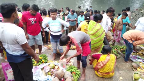 Close-up-view-of-people-standing-in-front-of-ganga-river-water-performing-rituals-with-kitchen-baskets-of-coconut-and-fruits-kept-on-the-steps-of-ganga-in-Kolkata