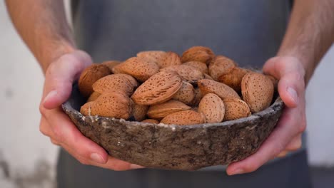 Man-Holding-A-Bowl-Of-Almond-Nuts-With-Shell