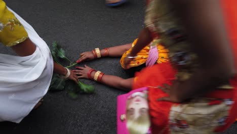 Close-up-shot-of-a-women-performing-ritual-of-chatt-puja-in-the-street-road-with-the-leaf's-and-kids-touching-her-in-Kolkata