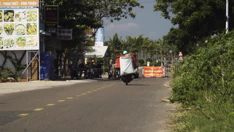Person-driving-motor-bike-in-Vietnam,-reaching-COVID-roadblock-between-Mui-Ne-and-Ham-Tien
