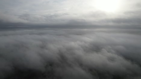 Aerial-pan-view-above-fog-low-level-cloud-sun-bursting-through
