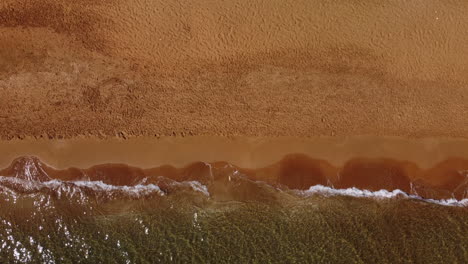 Aerial-top-view-of-waves-on-the-shore,-clay-beach,-Greece