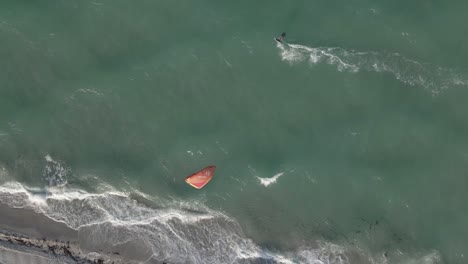 High-aerial:-Kite-surfer-parallels-beach-on-choppy,-windy-green-ocean