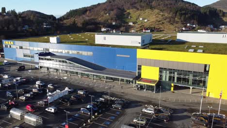Ikea-warehouse-from-closeup-to-overview-of-full-building-exterior-and-parking-lot---Reverse-aerial-revealing-building-with-highway-and-surroundings---Sunny-summer-evening-aerial-Norway