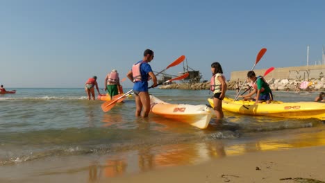 Tourists-on-holiday-at-Punta-Penna-beach-preparing-for-kayak-tour-on-hot-summer-day