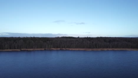Birdseye-View-of-the-Shoreline-of-a-Epic-Lake-With-Forest-in-the-Background---Truck-Shot