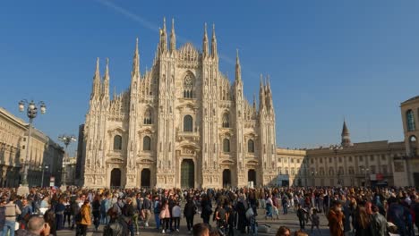 Tilt-down-slow-motion-scene-of-Duomo-di-Milano-or-Milan-Cathedral-with-people-in-crowded-square,-Italy