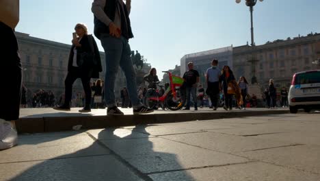 Ground-surface-pov-of-tourists-at-Duomo-square-in-Milan-with-Vittorio-Emanuele-II-monument-in-background,-Italy