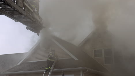 Thick,-Dark-Smoke-Pours-out-of-a-Burning-House-as-Firefighters-Use-Ladders-to-Access-the-Roof