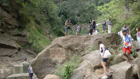 Tourists-exploring-Ravana-Falls-landscape-in-sunny-day,-Sri-Lanka