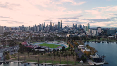 Melbourne-Aquatic-Center-slowly-revealing-itself-with-Melbourne-CBD-in-the-background-over-Albert-Park-Lake