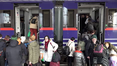 Refugees-fleeing-the-Russian-invasion-of-Ukraine,-including-the-elderly-and-children,-quickly-board-a-train-at-a-railway-station