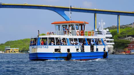 Ferry-of-tourists-sight-seeing-on-Sint-Annabaai-by-the-Queen-Juliana-Bridge-coming-in-to-dock-on-a-jetty-in-Willemstad-on-the-Caribbean-island-of-Curacao