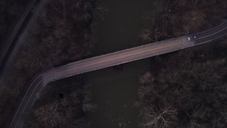 AERIAL:-Car-Drives-Over-Narrow-Bridge-at-Dusk