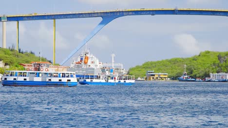 Ferries-cruising-along-Sint-Annabaai-near-the-Queen-Juliana-Bridge-in-Willemstad,-Curacao-in-the-Caribbean