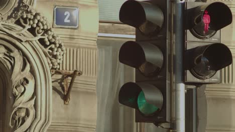 Changing-traffic-crossing-lights-sequence-on-Prague-street-outside-ornate-decorative-stonework-building-architecture