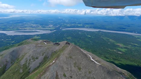 Small-airplane-flight-over-a-mountain-ridge-with-the-town-of-Palmer-Alaska-and-the-Matanuska-river-in-the-distance