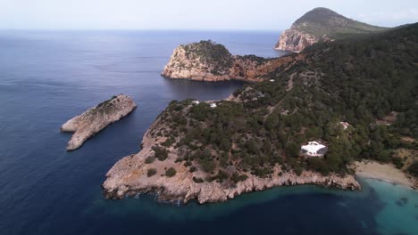 Beautiful-Nature-scape-of-Ibiza-Cliffs-and-Ocean,-Trees-Filling-Mountain-Side---Sliding-Aerial-Shot
