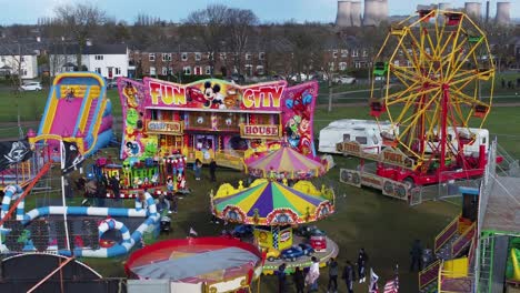 Small-town-fairground-Easter-holidays-funfair-rides-in-public-park-aerial-view-dolly-left