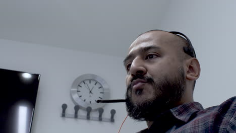 Asian-man-wearing-microphone-headset-working-night-shift-talking-with-customer-as-one-of-online-technical-support-team