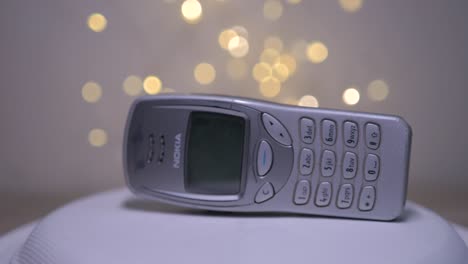 Obsolete-retro-reliable-analogue-classic-Nokia-mobile-phone-rotates-isolated-against-background-lights