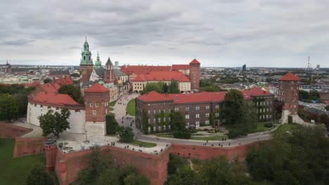 Aerial-view-of-Crakow-Royal-Wawel-Castle,-cathedral,-defensive-walls-and-a-courtyard-with-walking-people-on-cloudy-day