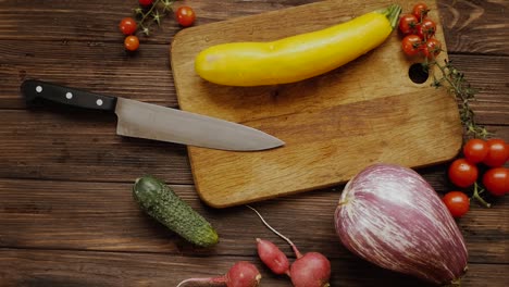 Yellow-eggplant-on-a-wooden-board-while-preparing-healthy-food-with-vegetables,-top-down-shot