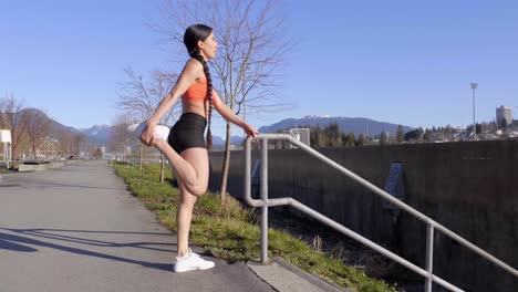 Sportliche-Junge-Frau,-Die-Die-Quadrizepsmuskeln-Der-Beine-Dehnt-Und-Das-Treppengeländer-Hält