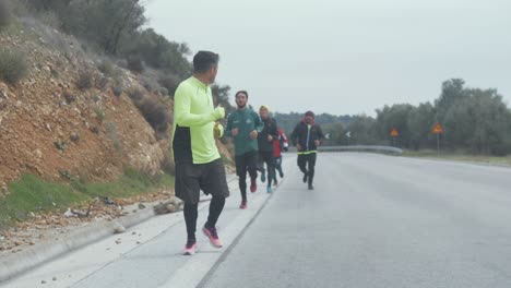 A-group-of-Afghan-men-running-along-road-in-Greece-Tracking-shot