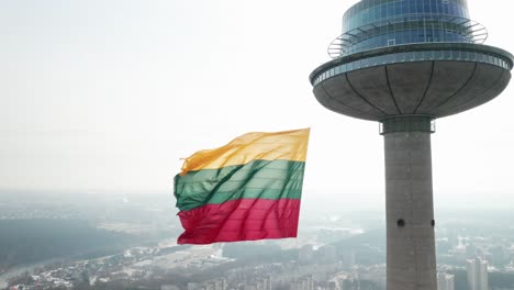 AERIAL:-Close-up-of-Lithuanian-Flag-Waving-in-Wind-on-TV-Tower-in-Vilnius