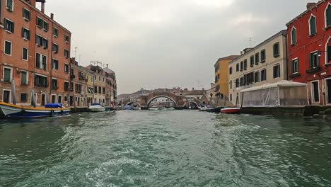 Punto-De-Vista-De-La-Superficie-Del-Agua-De-Venecia-Vista-Desde-Un-Ferry-De-Vela-Con-El-Puente-Ponte-Dei-Tre-Archi-En-El-Fondo,-Venecia-En-Italia