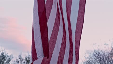 SLOW-MOTION:-Close-up-of-a-ragged-American-flag-as-the-camera-tilts-up,-revealing-an-eagle-emblem-at-the-top